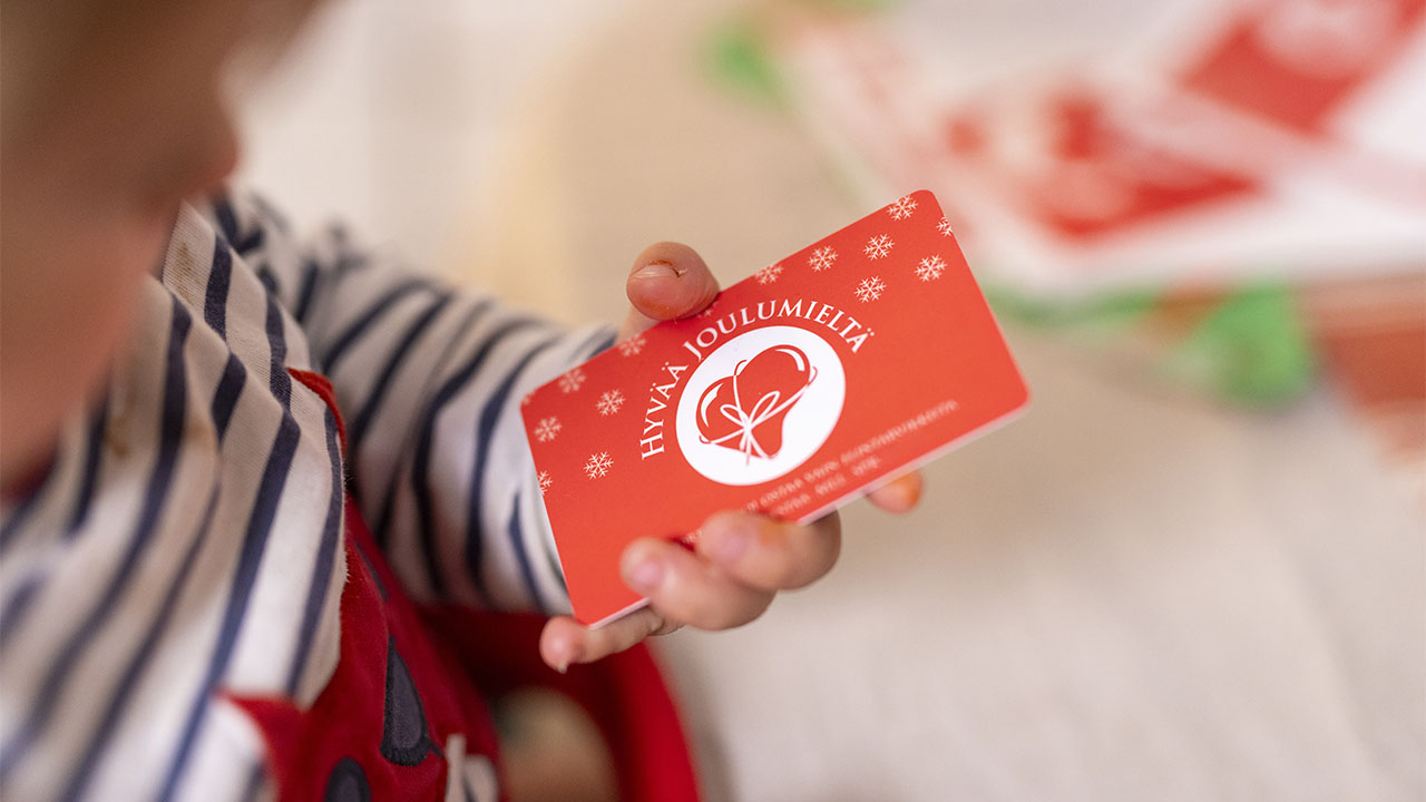 Hyvä joulumieli -lahjakortti lapsen kädessä